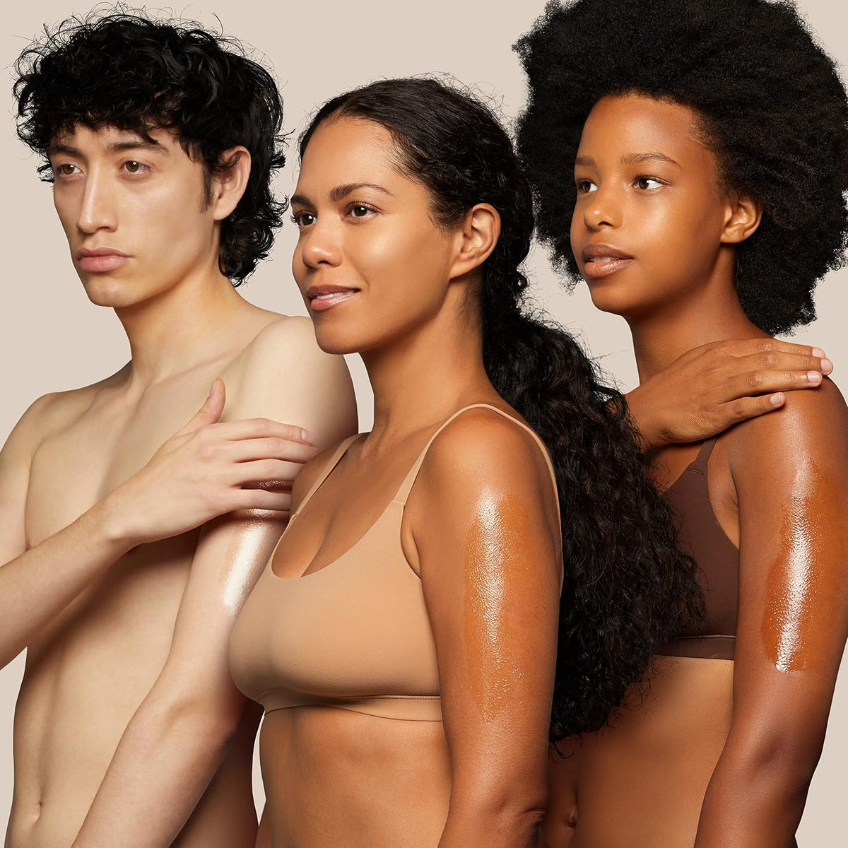 Derma:B Daily Moisture Body Oil on the shoulders and arms of three models with dewy skin