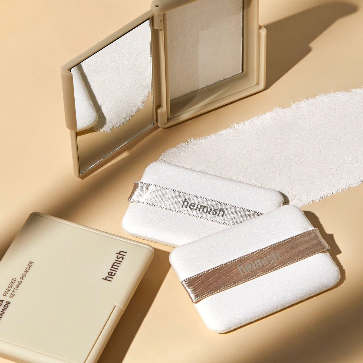 Heimish Moringa Ceramide Pressed Setting Powder compact with branded puffs and a swatch of the fine white powder