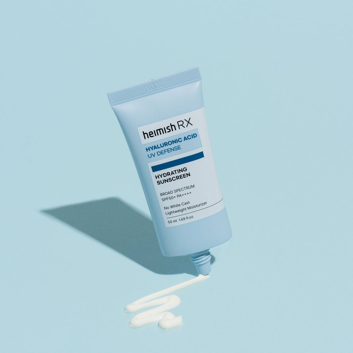 Heimish RX Hyaluronic Acid Hydrating Sunscreen tube squeezing out a line of white cream on a blue backdrop