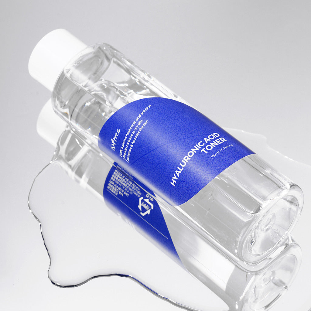 Isntree Hyaluronic Acid Toner bottle lying on a clear puddle of toner with its reflection