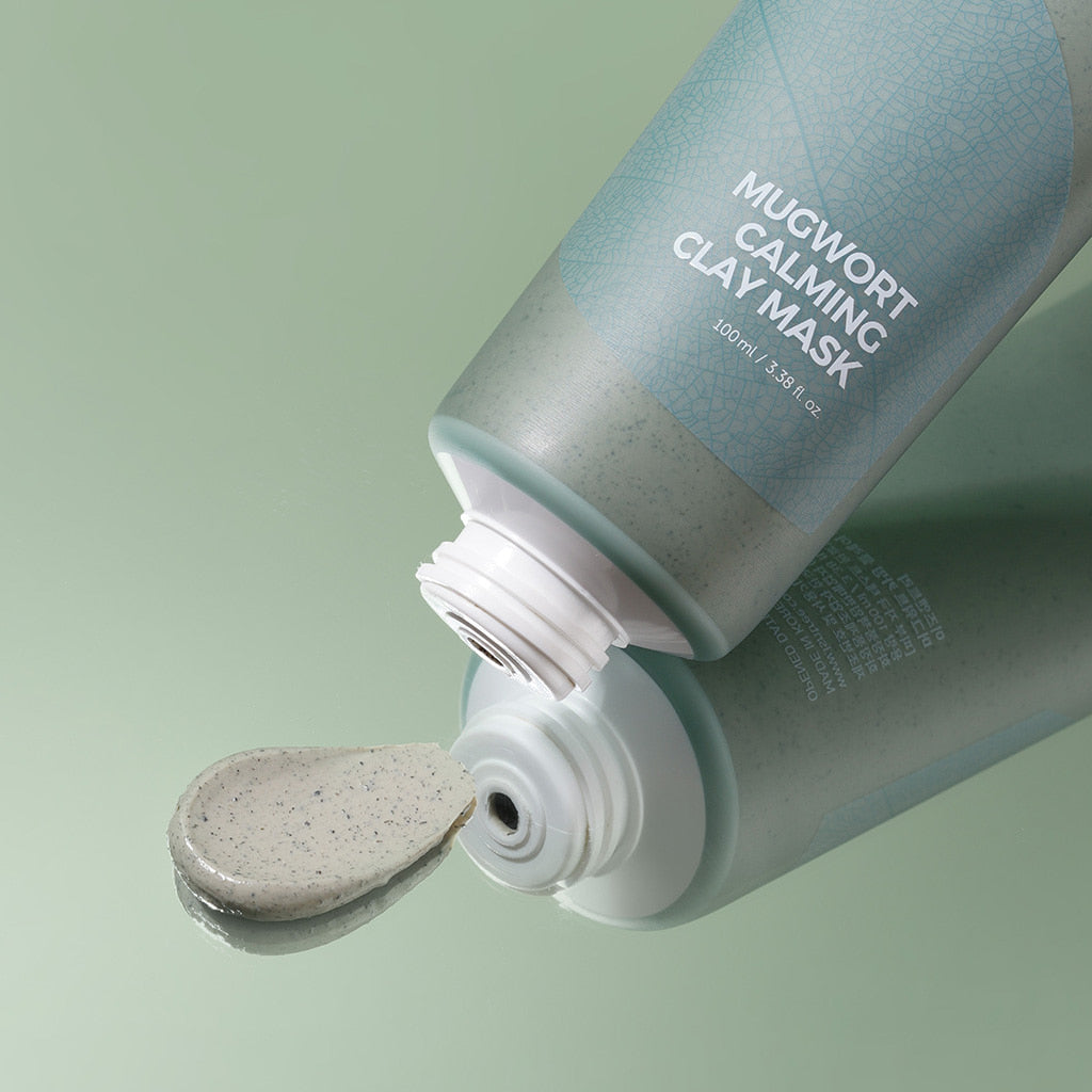 Isntree Mugwort Calming Clay Mask open tube with a dollop of speckled grey clay on a green background