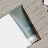Isntree Mugwort Calming Clay Mask tube lying on a wide swatch of grey clay