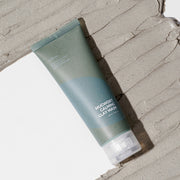 Isntree Mugwort Calming Clay Mask tube lying on a wide swatch of grey clay