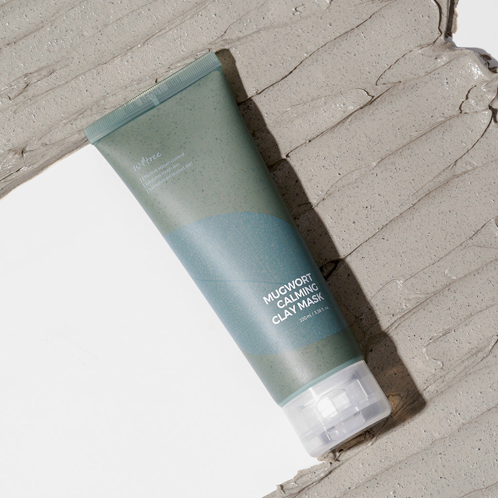Isntree Mugwort Calming Clay Mask tube lying on a wide swatch of grey clay