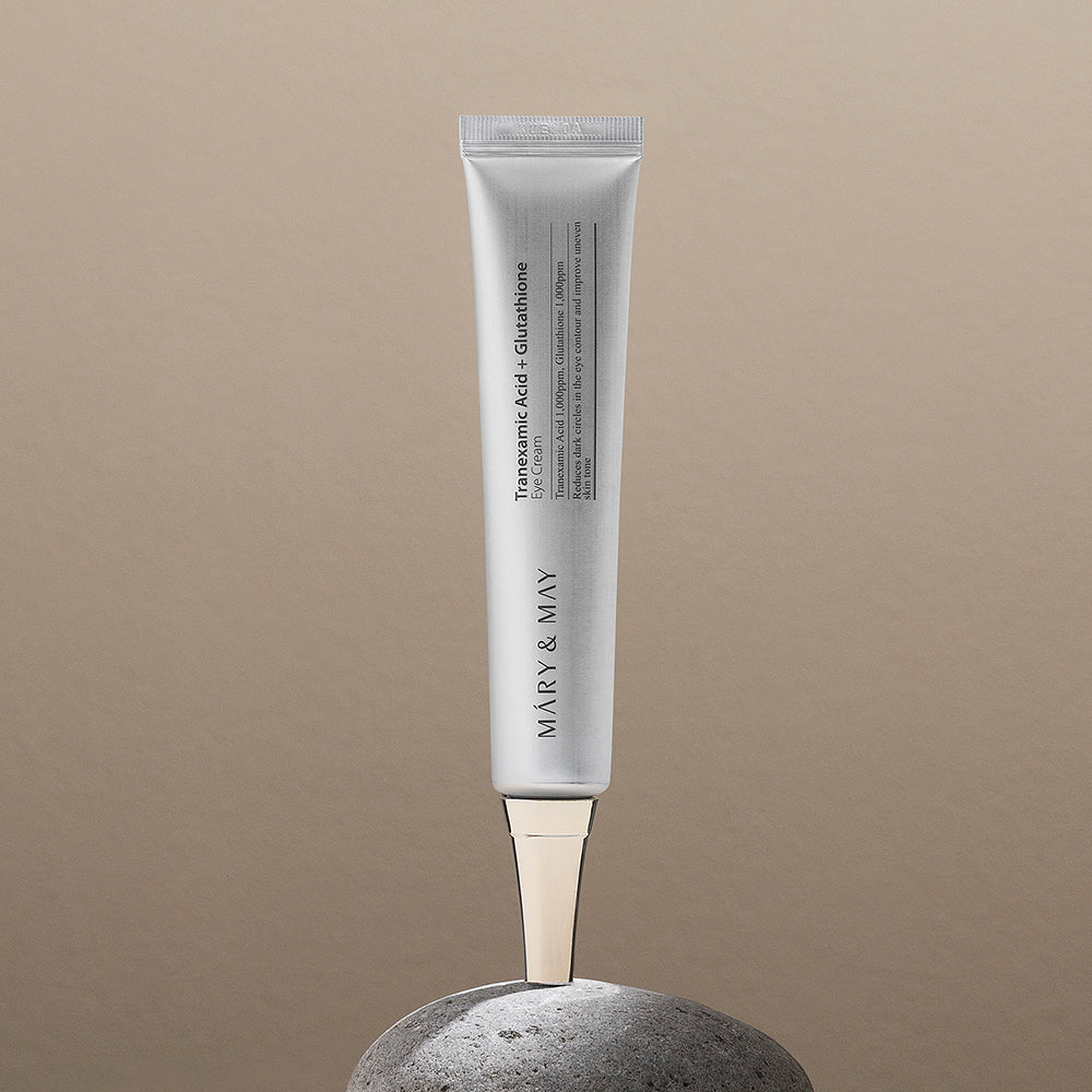 Mary&May Tranexamic Acid + Glutathione Eye Cream tube standing on a grey stone