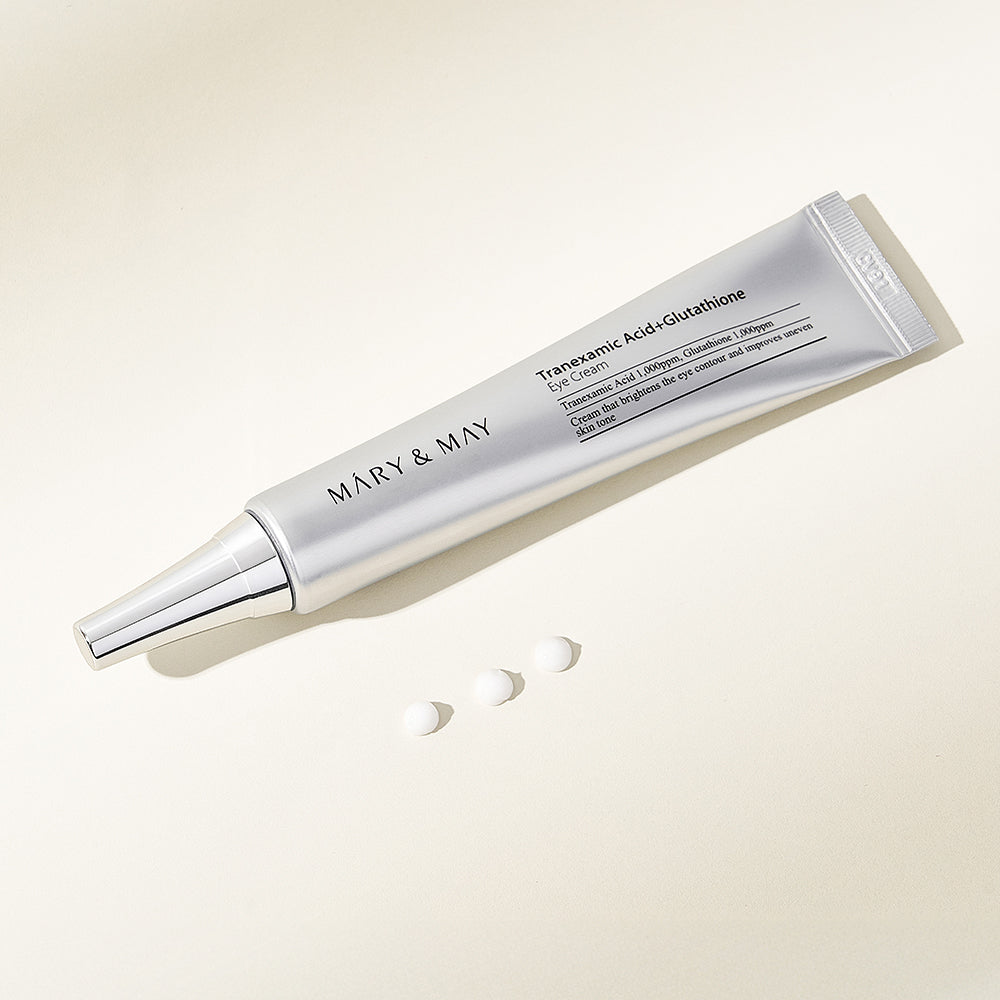 Mary&May Tranexamic Acid + Glutathione Eye Cream tube lying beside dots of cream