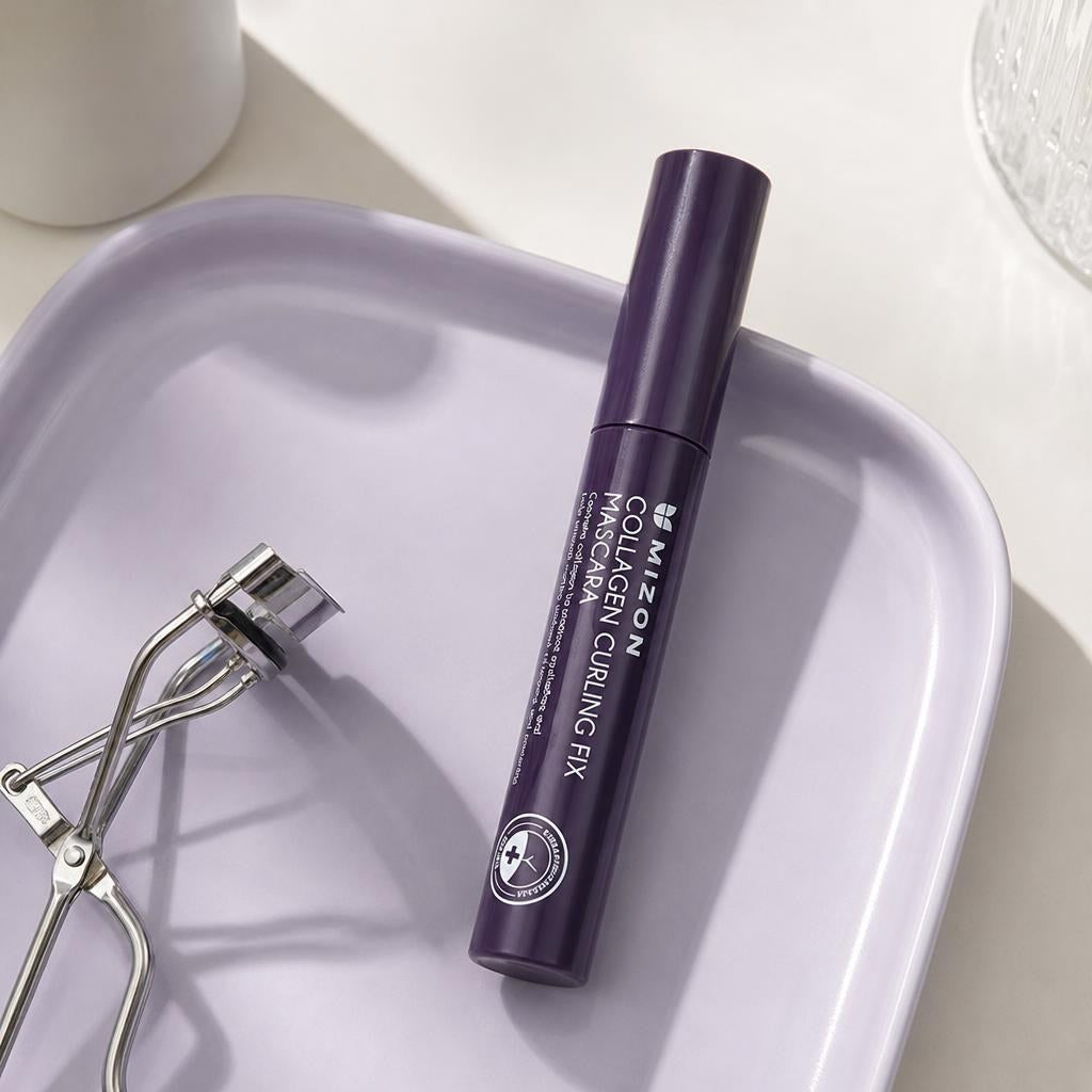 Mizon Collagen Curling Fix Mascara 6ml purple tube on a lilac tray beside an eyelash curler