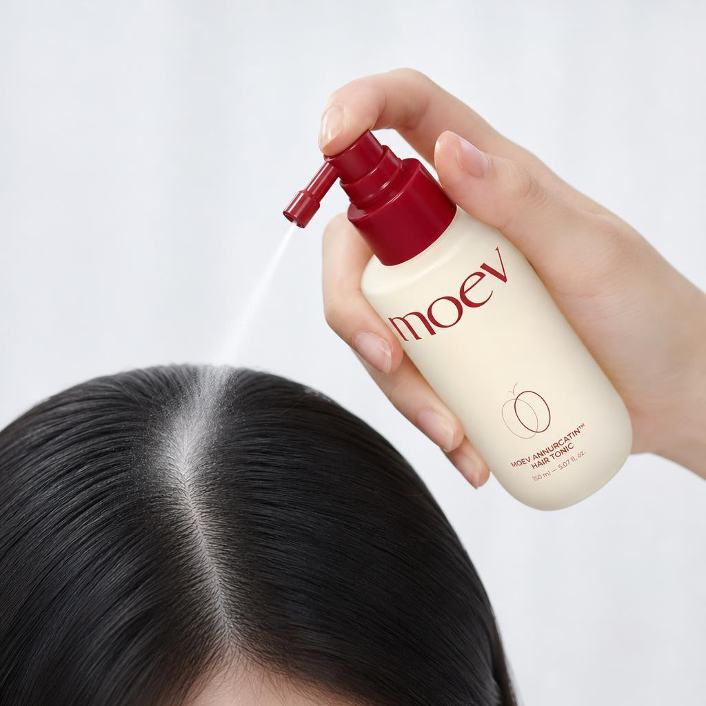 MOEV Annurcatin Hair Tonic 150ml bottle spraying tonic onto the scalp along a hair part