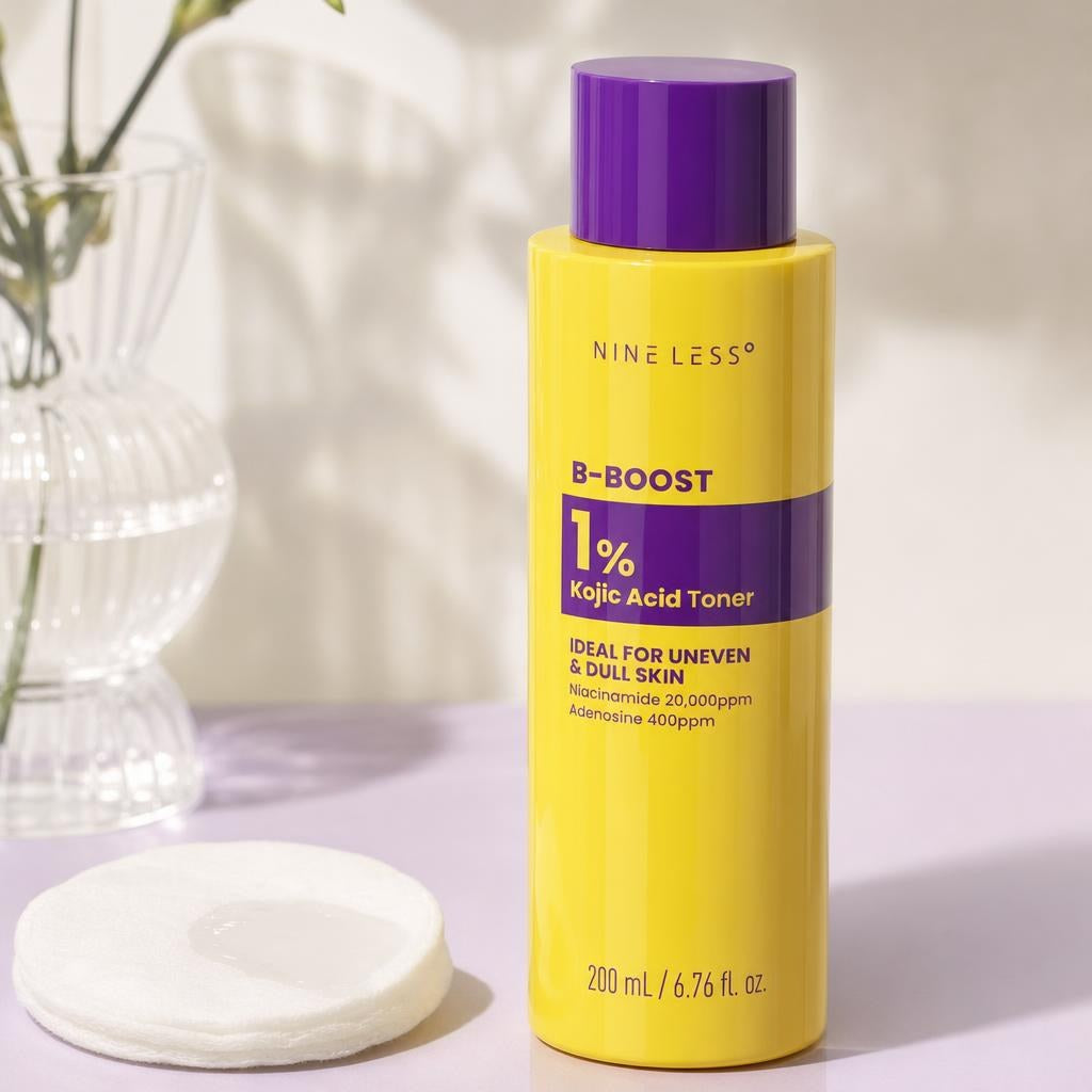 Nine Less B-Boost 1% Kojic Acid Toner 200ml yellow bottle with purple cap beside a cotton pad