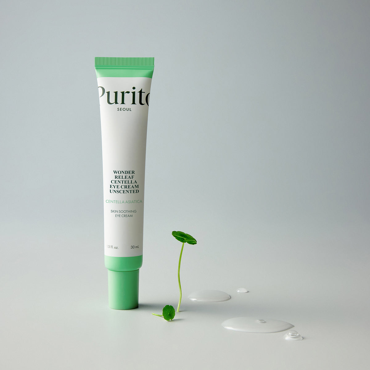 Purito Seoul Wonder Releaf Centella Eye Cream Unscented tube standing beside a centella sprout and cream drops