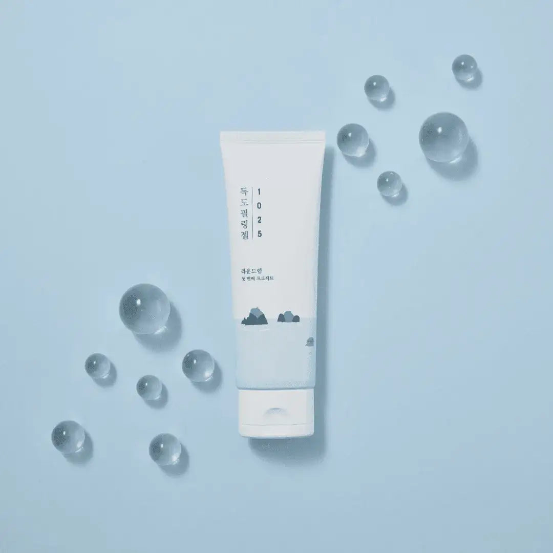 Round Lab 1025 Dokdo Peeling Gel tube surrounded by water droplets on a blue background