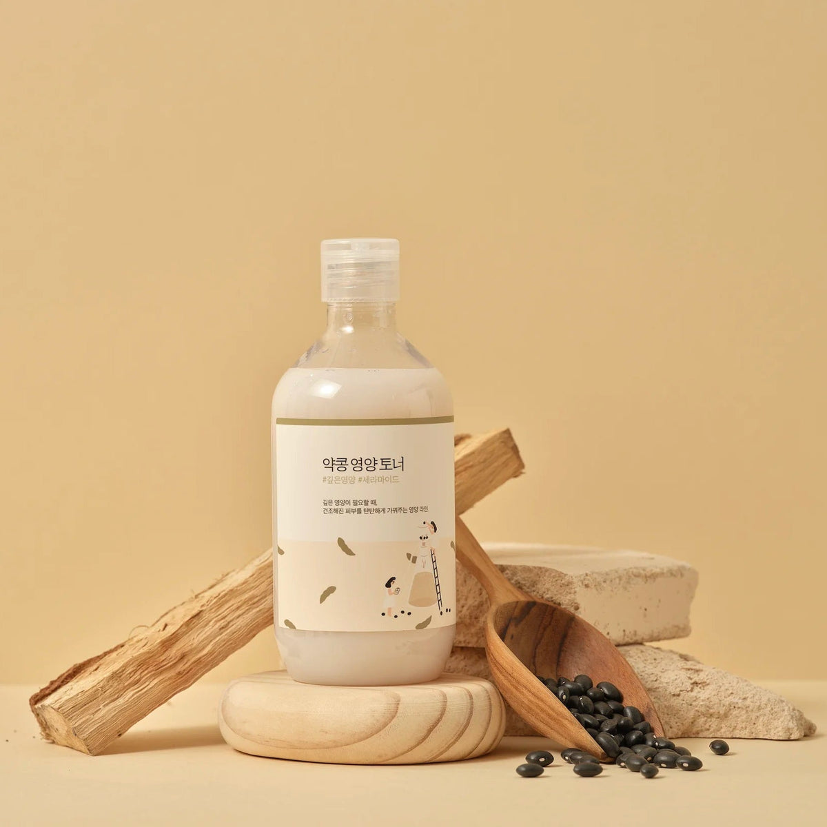 Round Lab Soybean Nourishing Toner bottle on a wooden stand with black soybeans and a wooden scoop