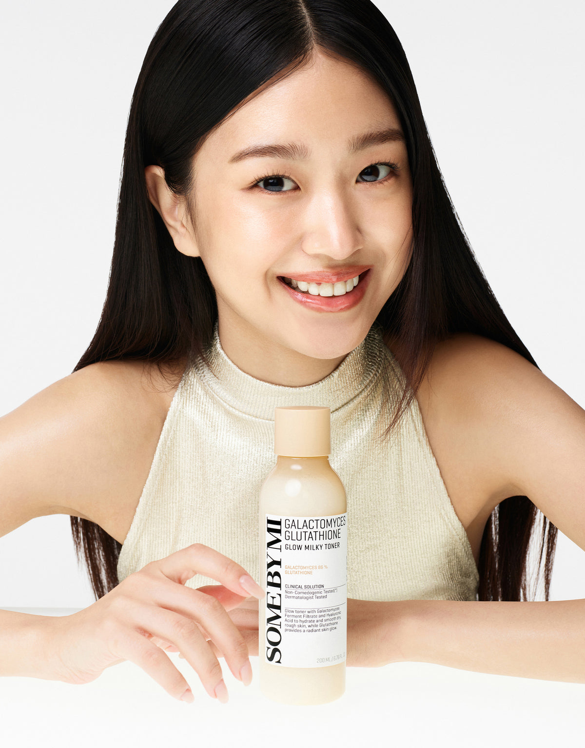Some By Mi Galactomyces Glutathione Glow Milky Toner held on a table by a smiling model
