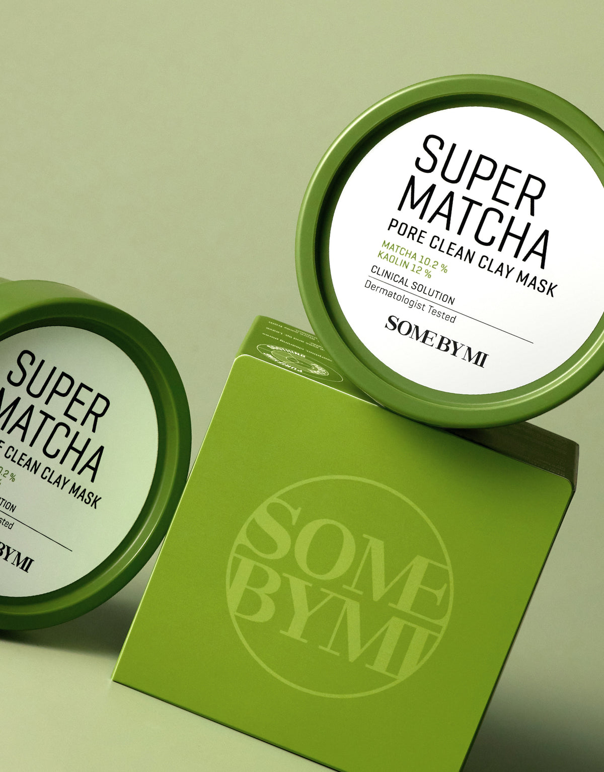 Some By Mi Super Matcha Pore Clean Clay Mask jars with the green outer box on a sage background