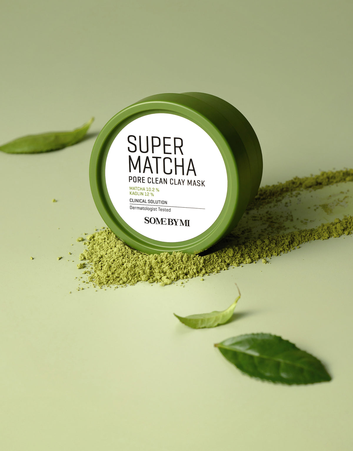 Some By Mi Super Matcha Pore Clean Clay Mask jar resting in matcha powder with green tea leaves