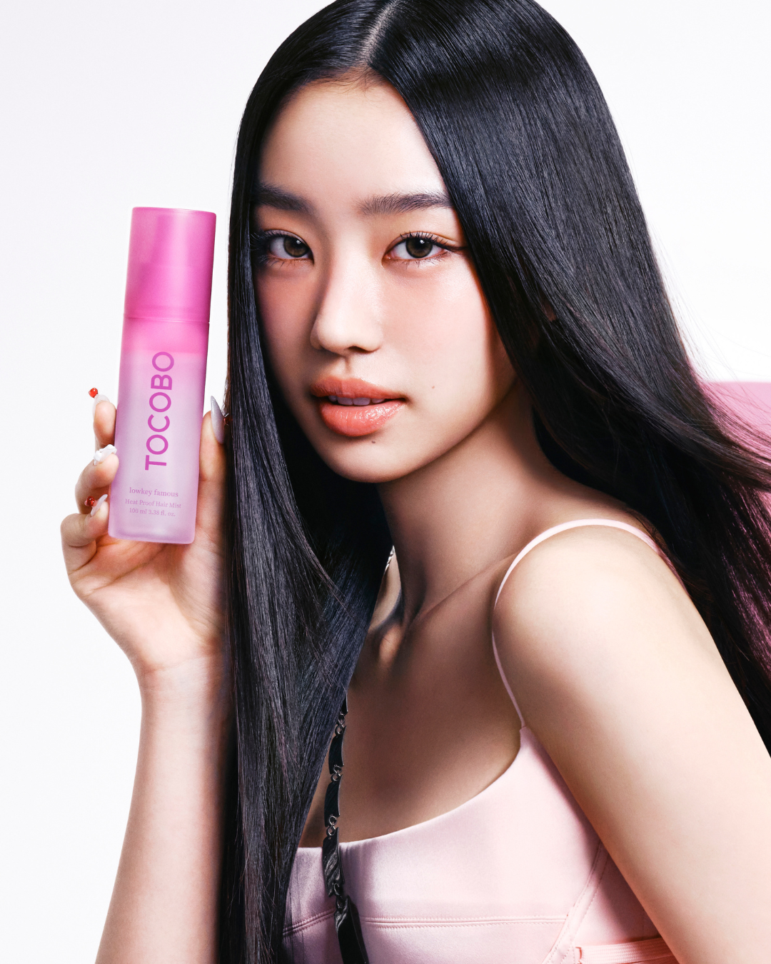 Tocobo Heat Proof Hair Mist pink bottle held by a model with long, glossy hair