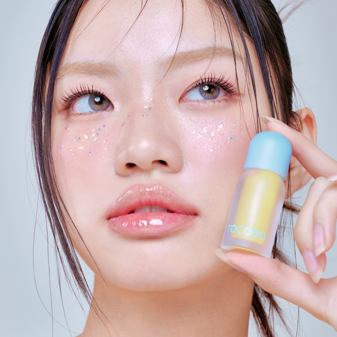 Tocobo Juicy Berry Plumping Lip Oil 11 Honey Lemon held by a model with glossy lips